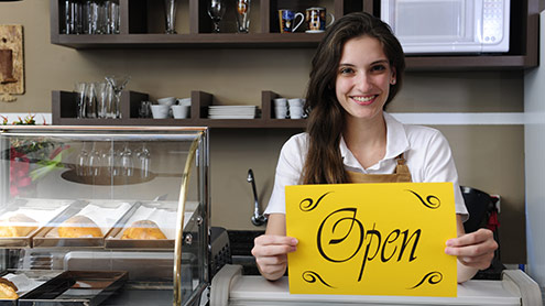 Female barista holding "Open" sign