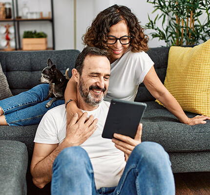 Man and woman casually sitting together on the couch watching a tablet