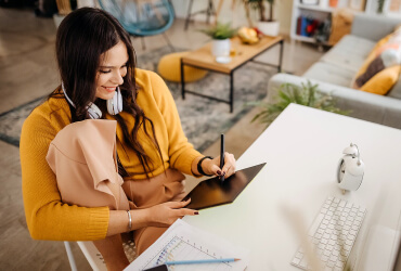 Woman sitting at a her desk at home writing on a tablet with a stylus