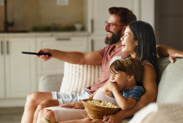 Family watching TV on the couch while eating popcorn