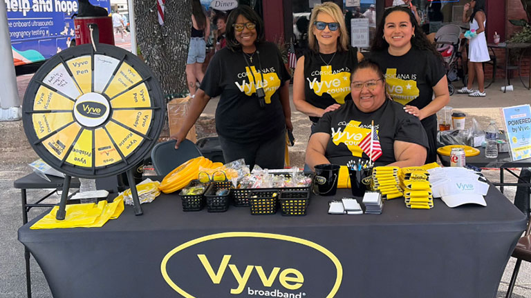 Vyve employees pose for a photo at their Vyve Broadband branded booth at Derek Days in Corsicana, Texas.
